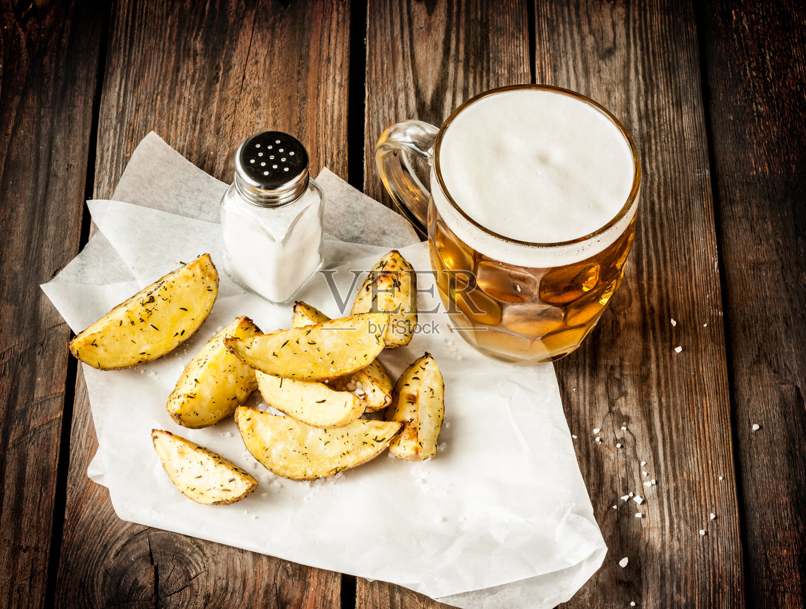 朴素的木桌上放着啤酒杯和烤土豆照片摄影图片