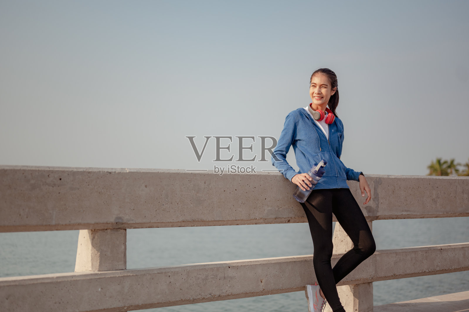 年轻女子喝水和站立休息后,晨练慢跑在城市。一个生活在首都的健康城市。锻炼、健身、慢跑、跑步、生活方式、健康理念。照片摄影图片