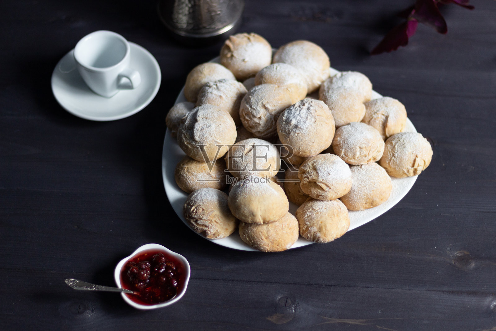 白色盘子上放糖粉烤蜂蜜蛋糕,背景为黑色,配上覆盆子果酱和咖啡照片摄影图片