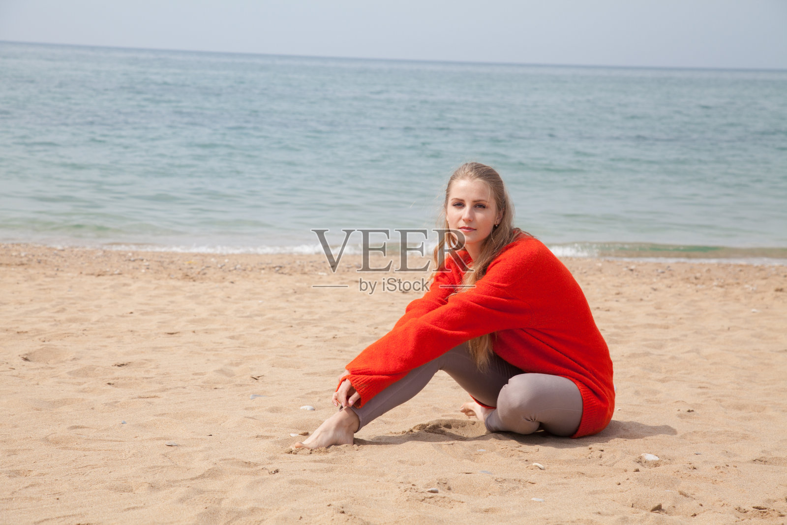 美丽的金发女人独自坐在沙滩上照片摄影图片