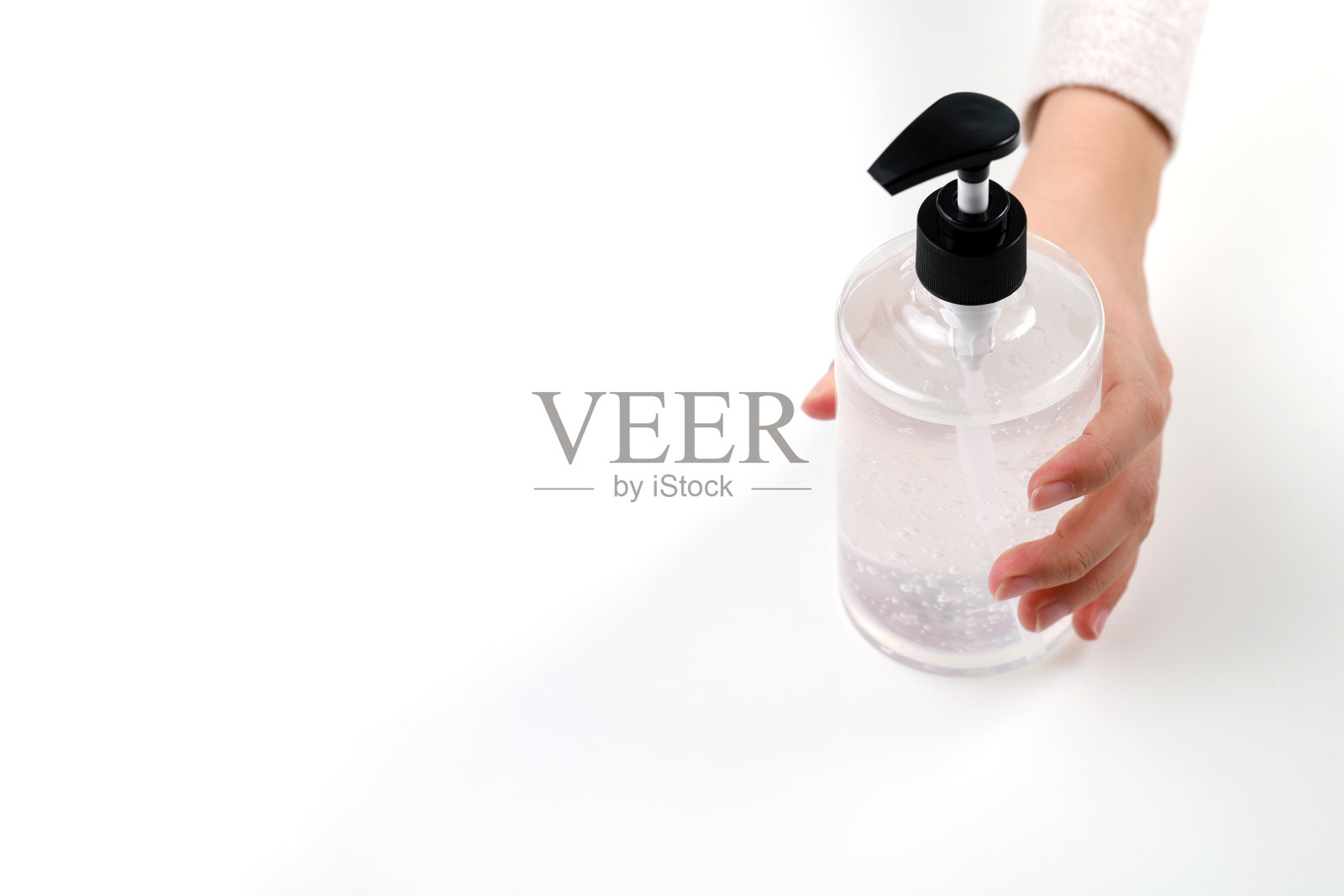 手拿一瓶消毒液,涂在白色的背景上照片摄影图片