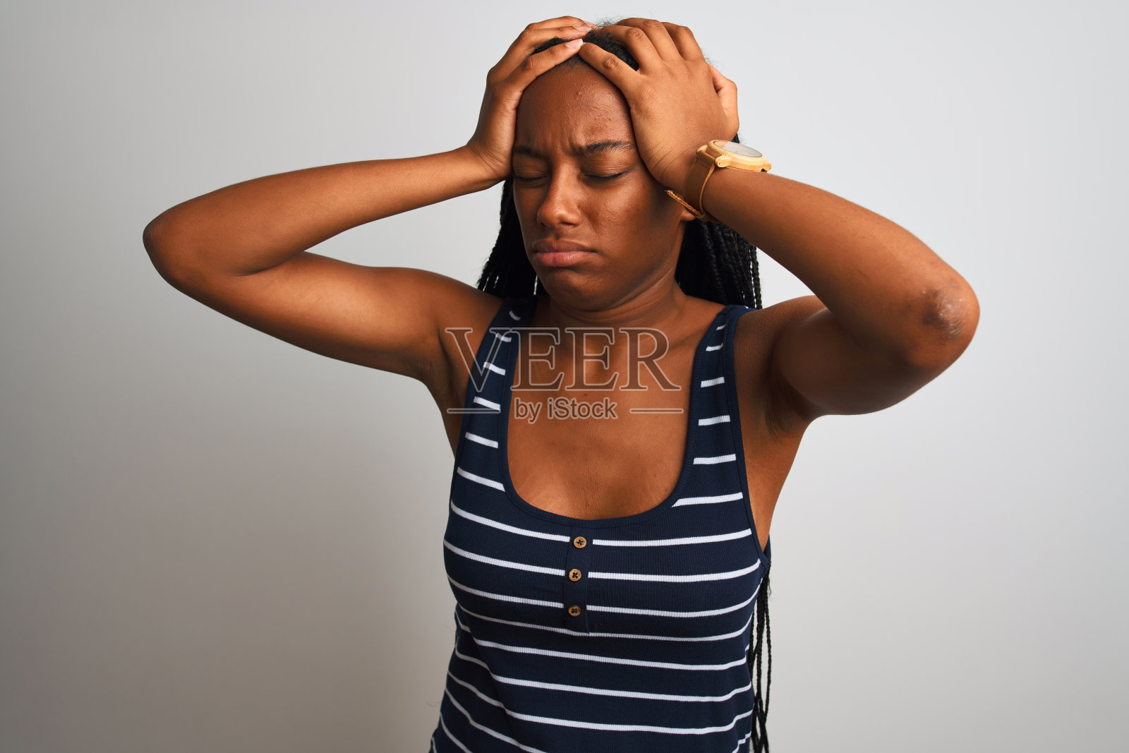 年轻的非洲裔美国妇女穿着条纹t恤站在孤立的白人背景下忍受着头痛绝望和压力因为疼痛和偏头痛。手放在头上。照片摄影图片