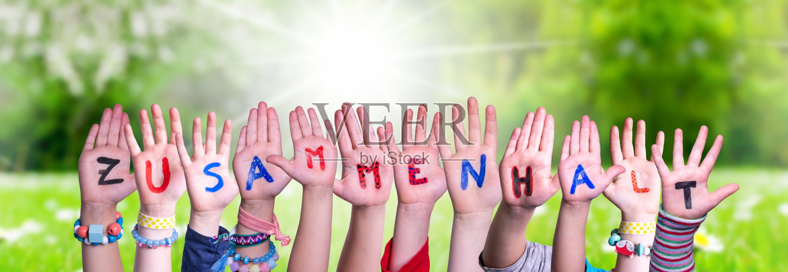 孩子们手握单词Zusammenhalt意思是在一起,草地照片摄影图片