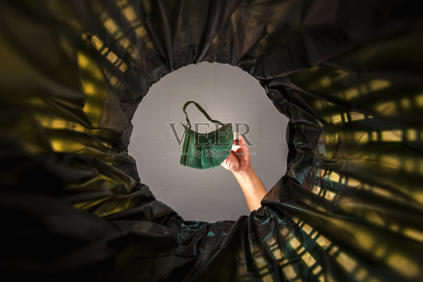 把口罩扔进垃圾桶。从垃圾桶里看到蠕虫。照片摄影图片