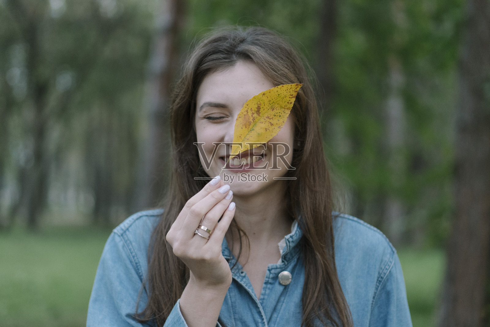 一个美丽微笑的女人的肖像,手里拿着一张黄色的床单。中秋、落叶,美丽的风景以公园为背景照片摄影图片