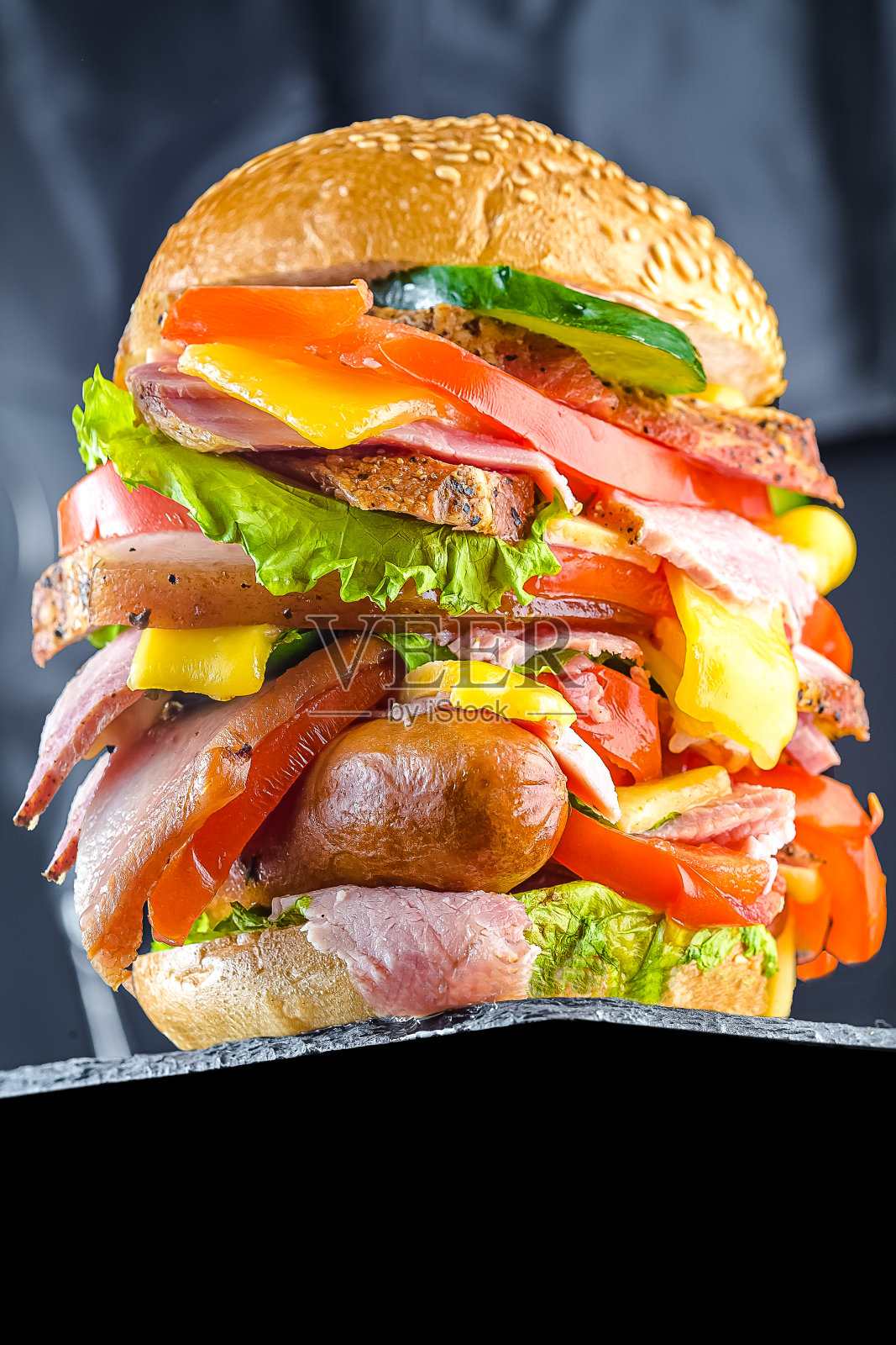 大的乡村风格,三明治或汉堡,与黑面包或小圆面包,各种肉,猪油,熏制美食,蔬菜,硬奶油奶酪,在一个黑色的木桌和黑暗孤立的背景照片摄影图片