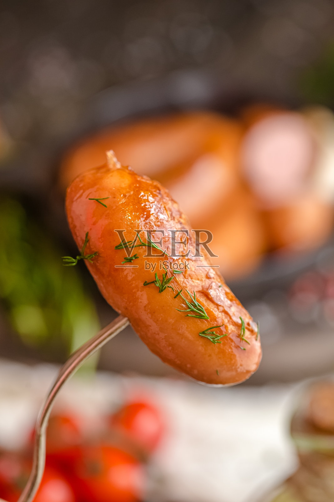 用叉子煎香肠,用平底锅在朴素的木头桌子上煎,或者用砧板照片摄影图片