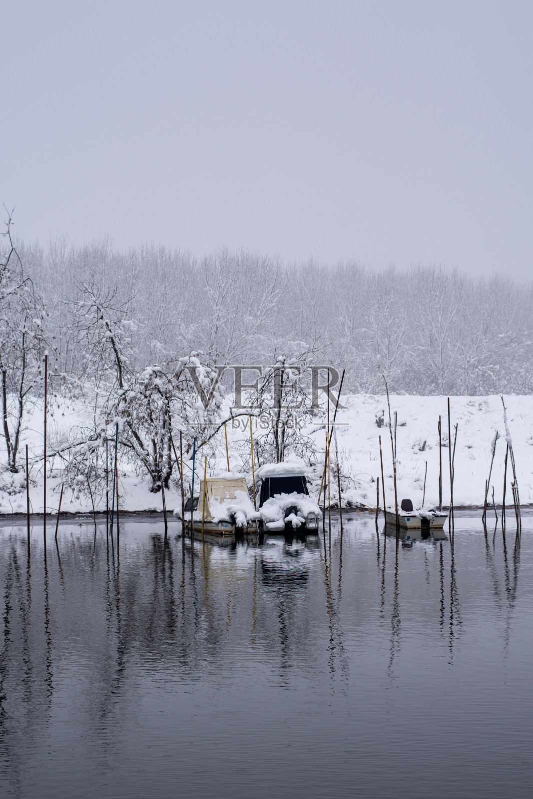 冬天的背景上有雪,河边有船。雾蒙蒙的冬日里,河上结了霜,下了雪。照片摄影图片