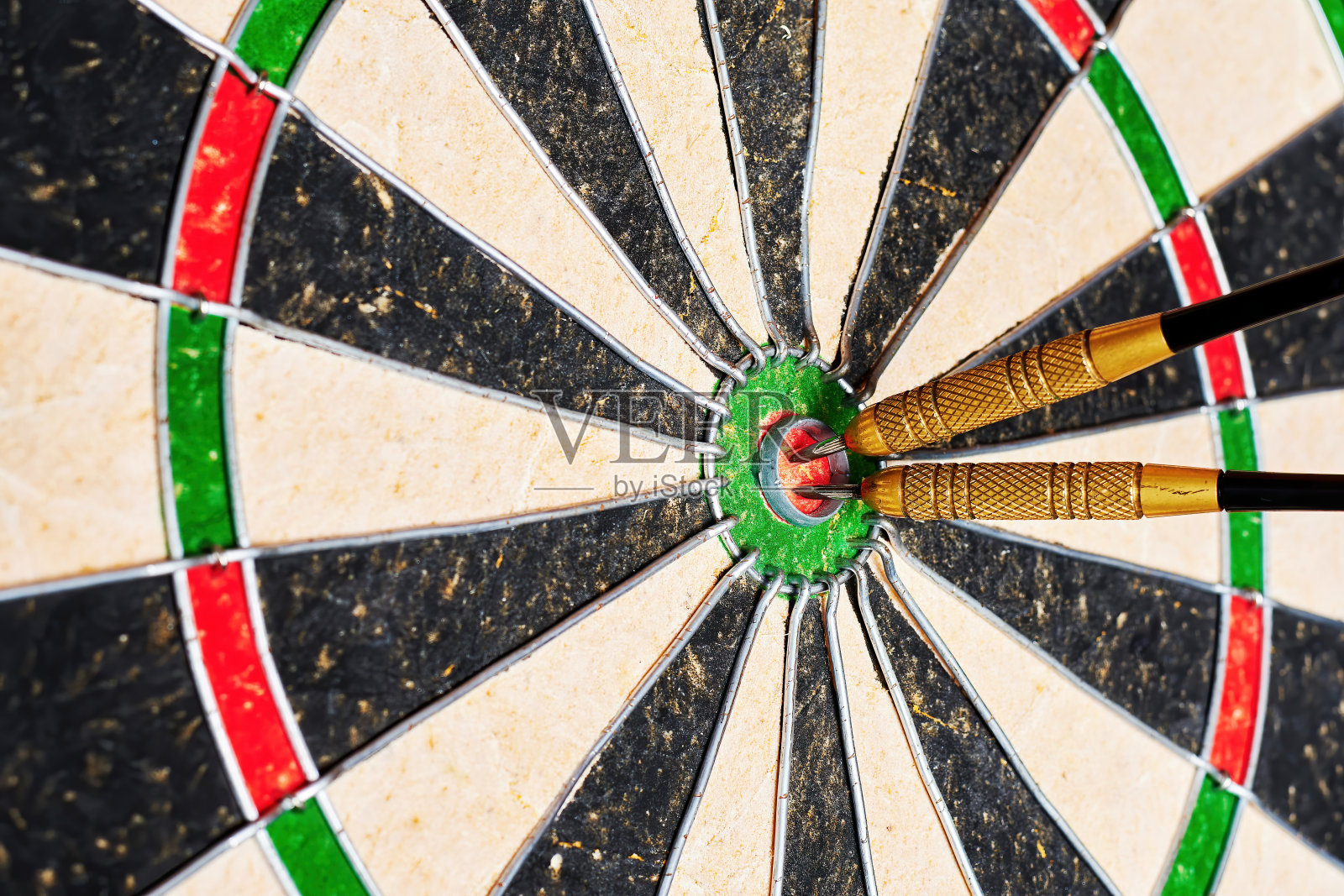 破旧的飞镖,有几枚飞镖直接掷向靶心。象征着竞争精神、决心和胜利。背景纹理照片摄影图片