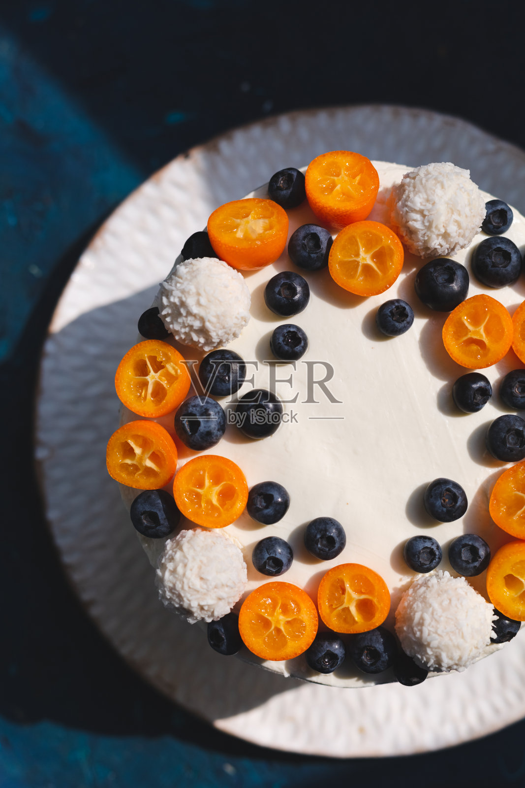 一个自制的蛋糕,上面覆盖着凝乳,装饰着新鲜的水果,浆果和椰子糖果照片摄影图片