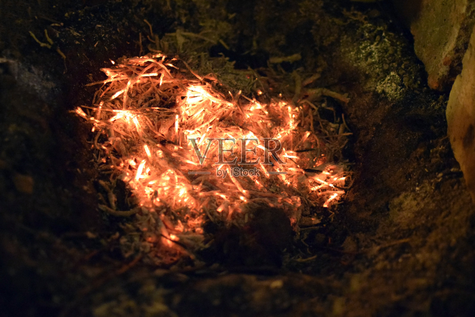在地上的一个坑中熄灭的火。燃烧木板,干树叶和草照片摄影图片