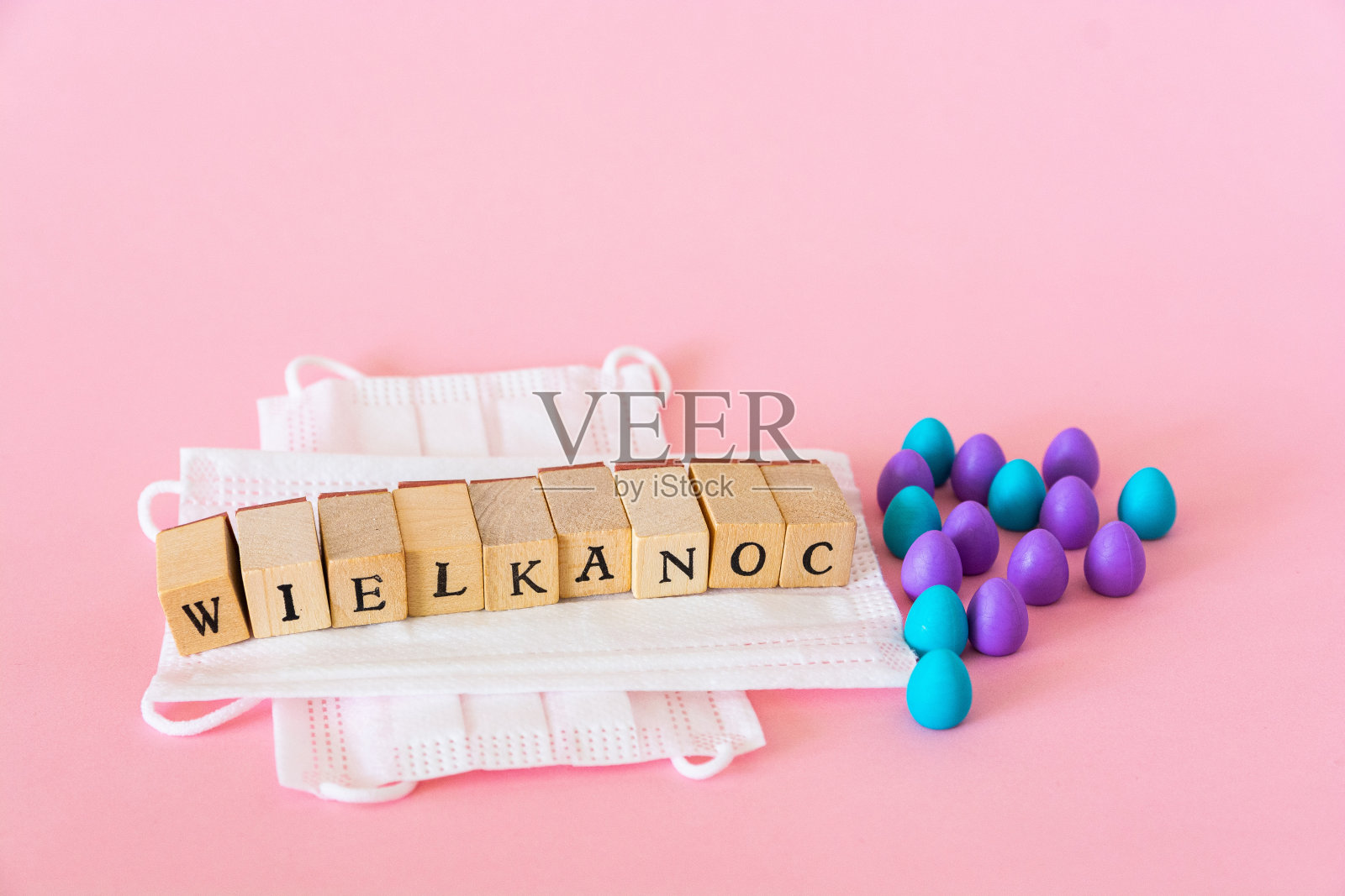 塑料鸡蛋放在防护口罩上,“wielkanoc”在波兰语中的意思是复活节照片摄影图片
