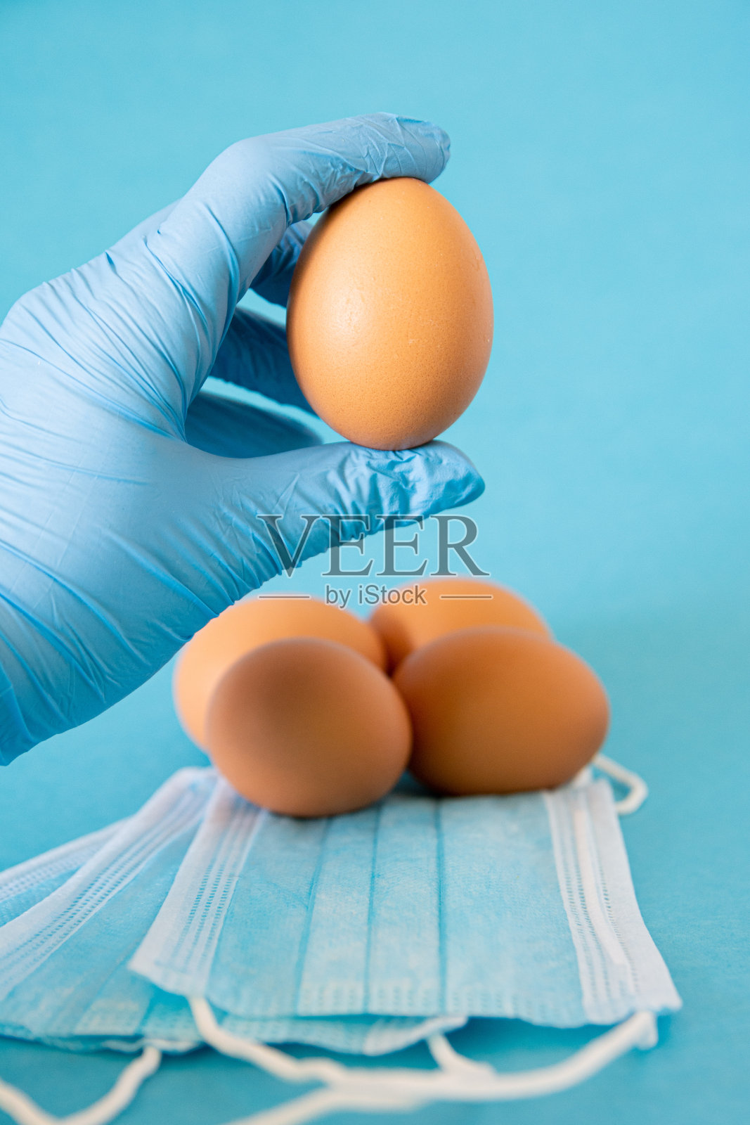 手拿保护手套手拿鸡蛋,是covid-19复活节概念照片摄影图片