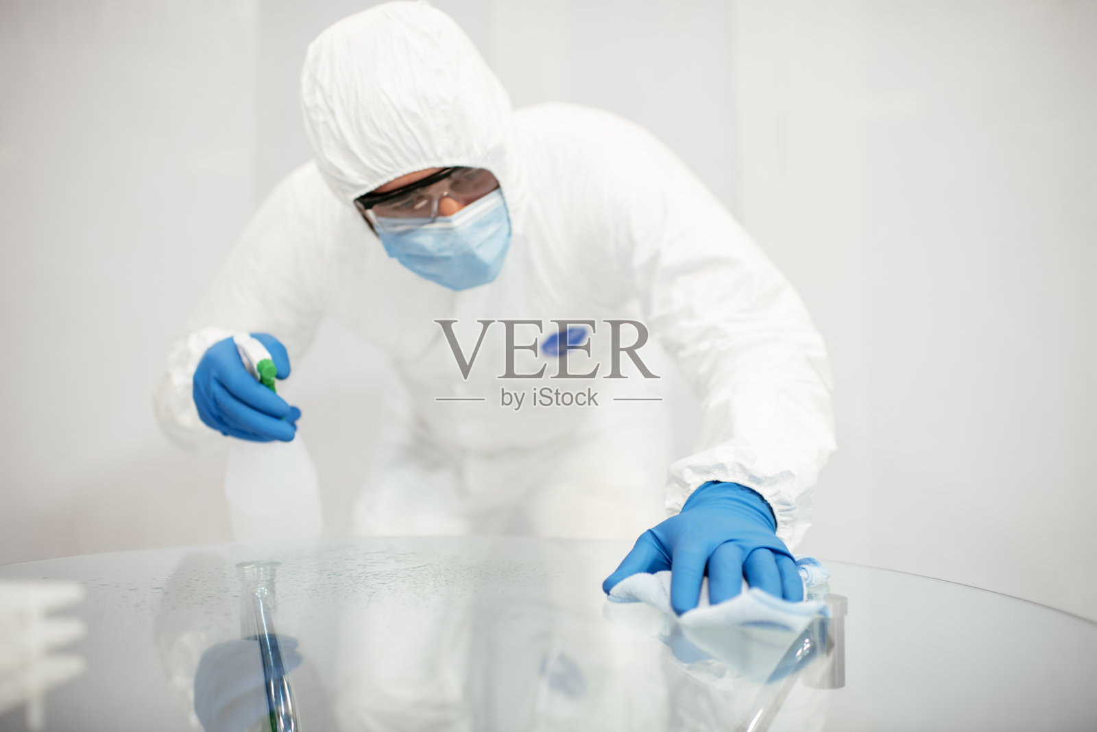 清洁表面。男子用手套和消毒液擦拭消毒桌子,防止细菌和细菌感染库存照片照片摄影图片