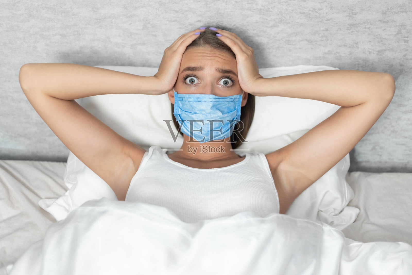 害怕的女人在室内的床上恐惧地摸着头照片摄影图片