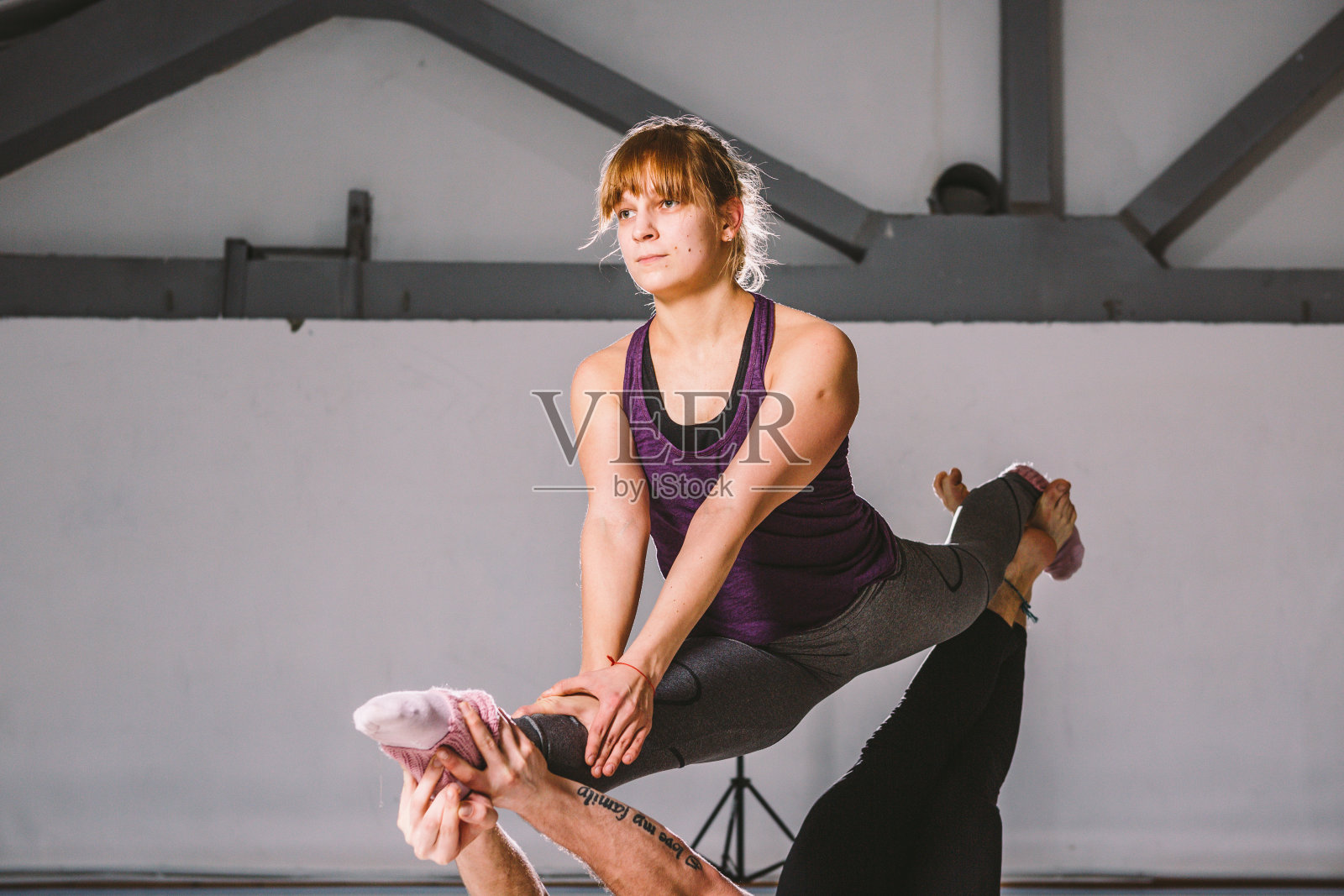 主题运动和健康的生活方式。杂技和acroyoga。年轻运动夫妇练习acroyoga手倒立。男性和女性杂技演员一起在垫子上做Acroyoga。家庭Acroyoga室内照片摄影图片