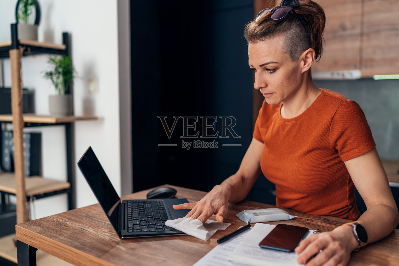 在家工作时擦拭并消毒笔记本电脑的女人照片摄影图片