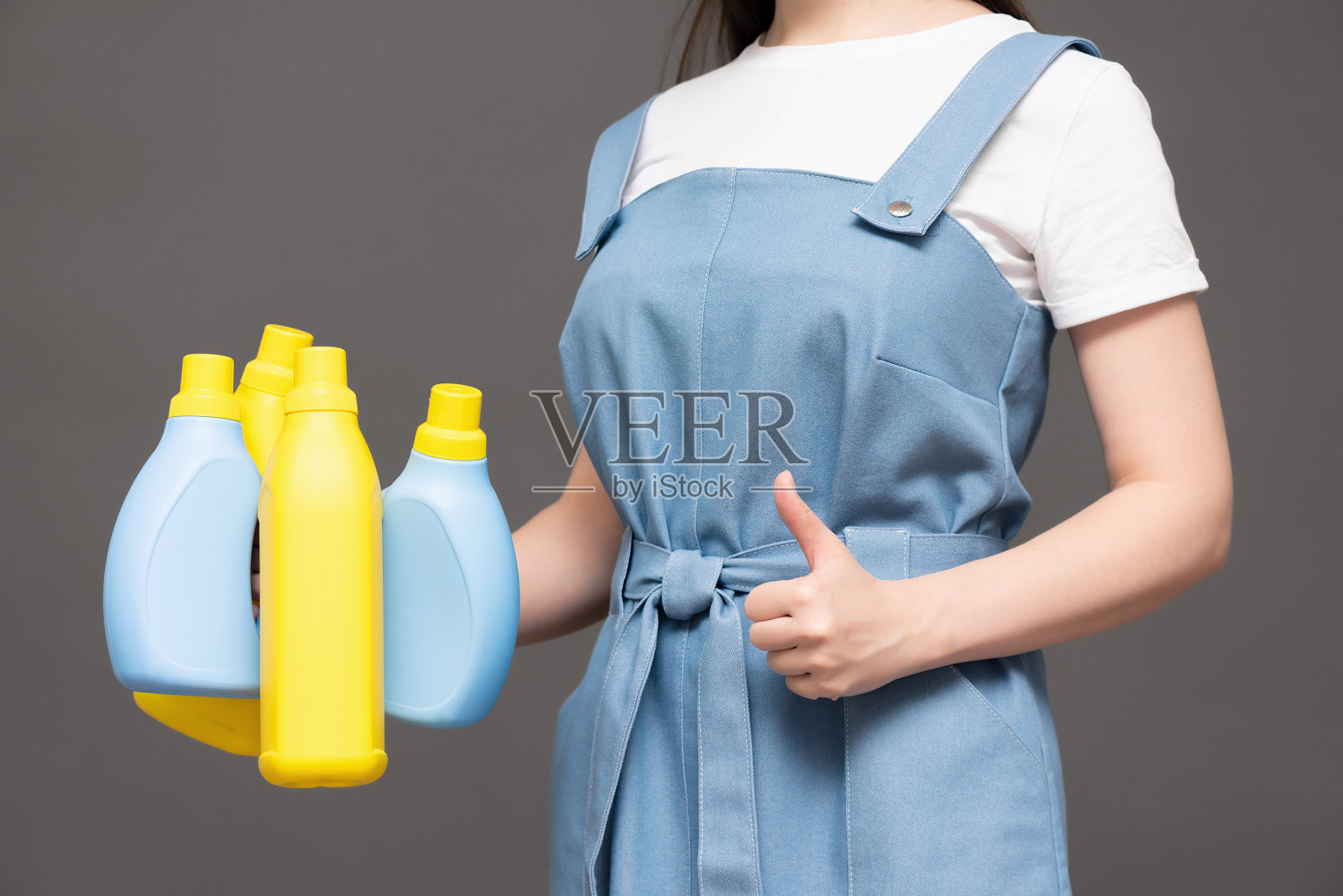 手中拿着洗洁精瓶。照片摄影图片