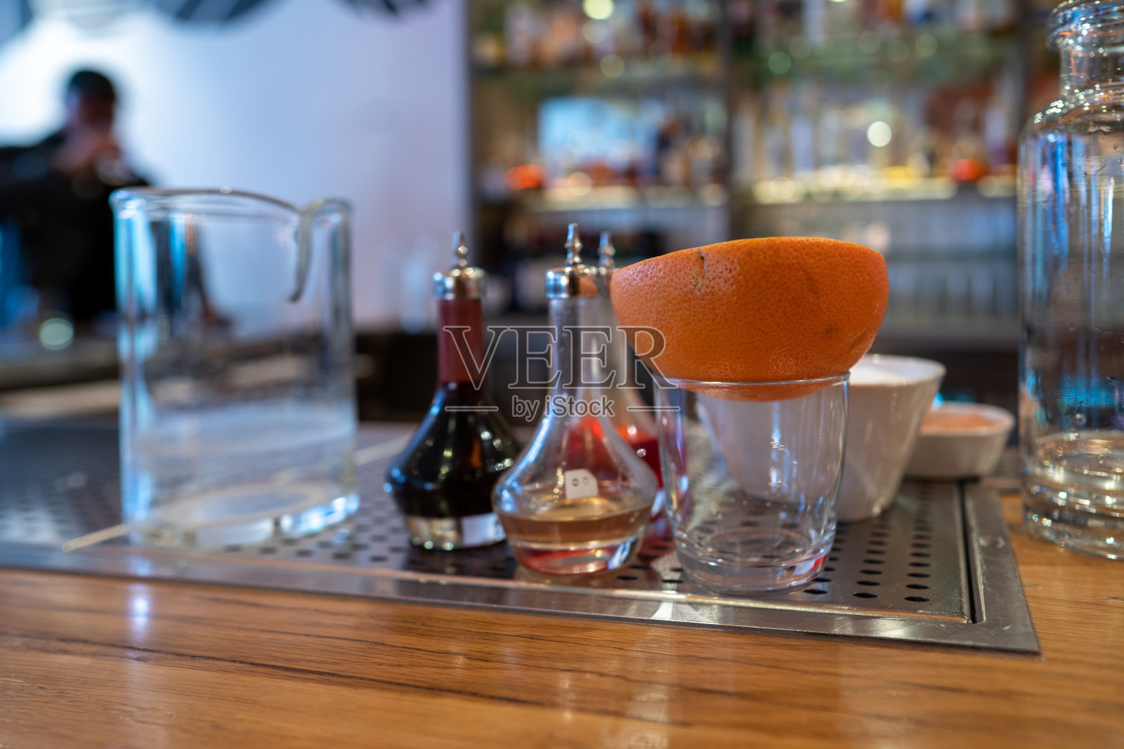 半个橙子放在玻璃杯里,旁边是吧台上的各种鸡尾酒和饮料工具照片摄影图片