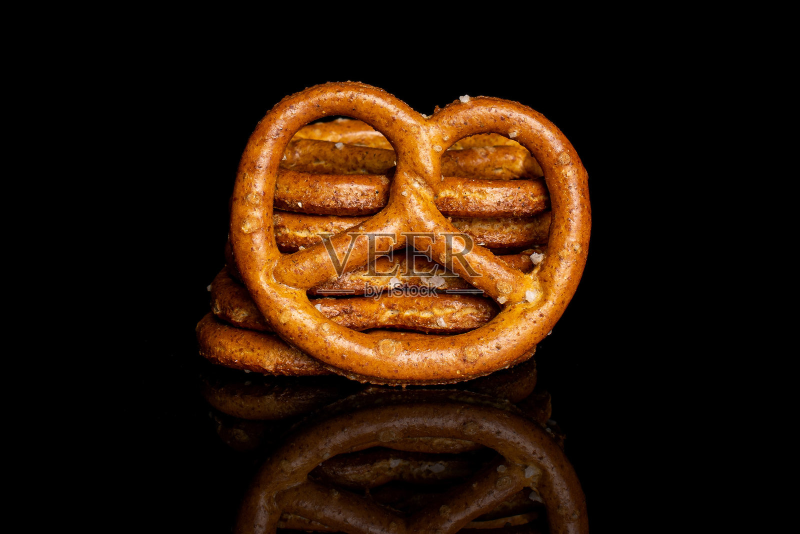 黑色玻璃上的咸味棕色椒盐卷饼照片摄影图片