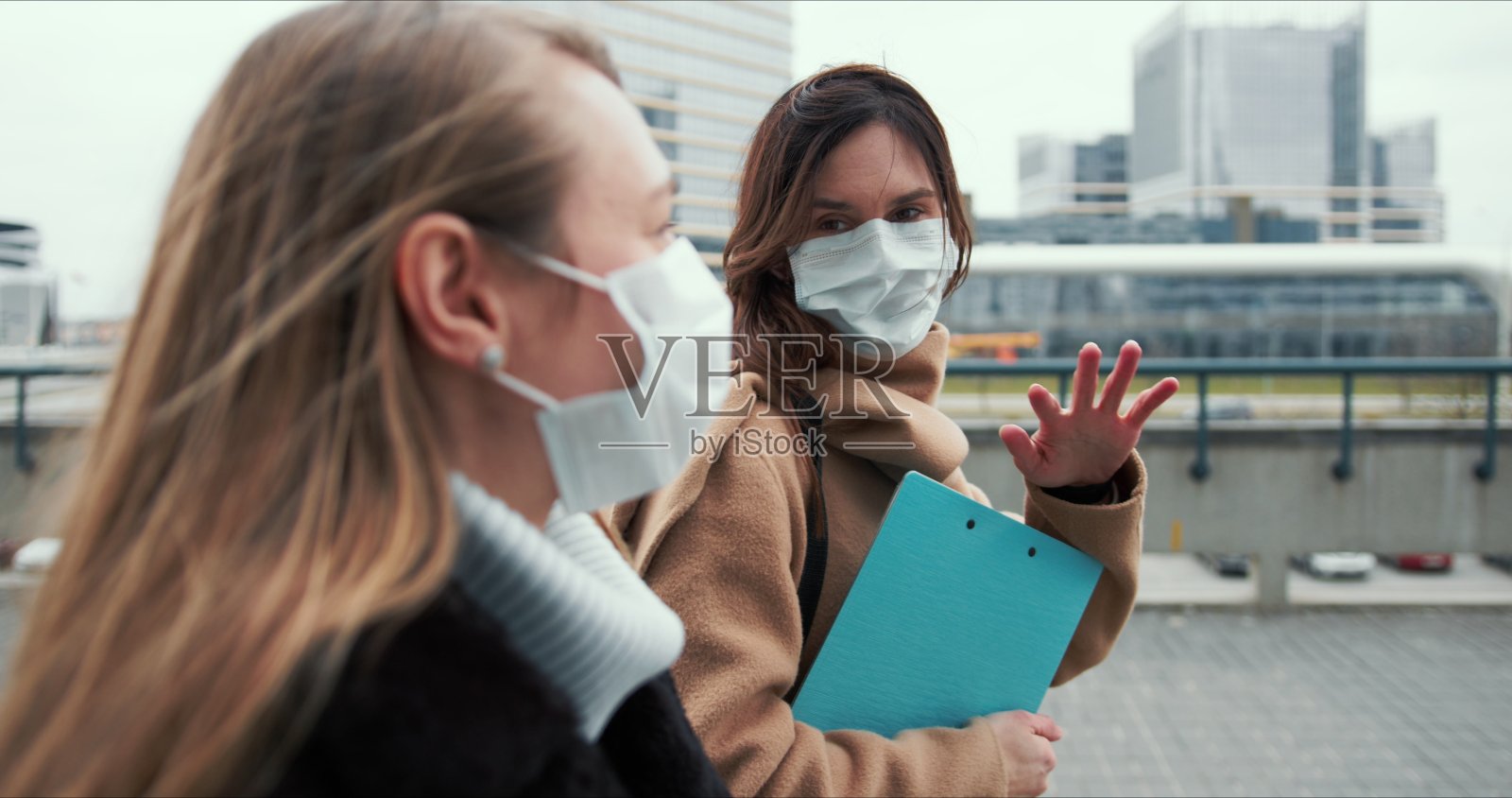 侧影两名年轻的白种女医生戴着口罩走在空荡荡的城市街道上照片摄影图片