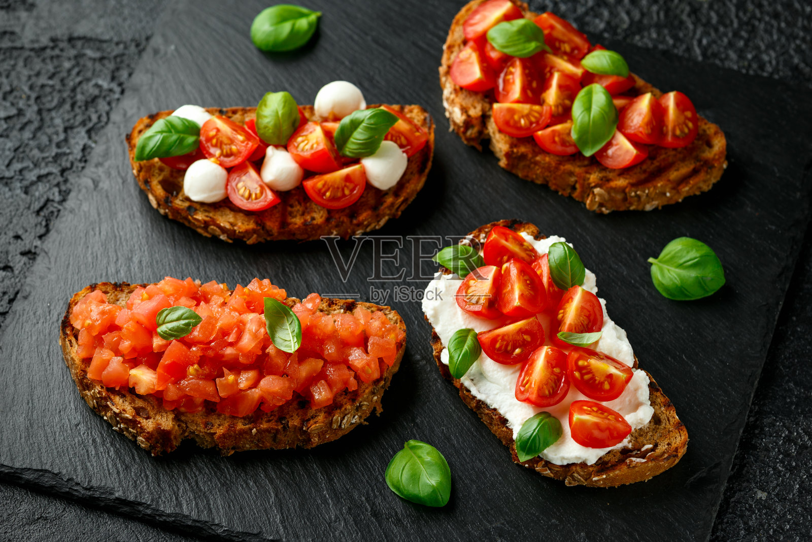 意式烤面包配乳清干酪、马苏里拉奶酪、罗勒、樱桃和番茄片照片摄影图片