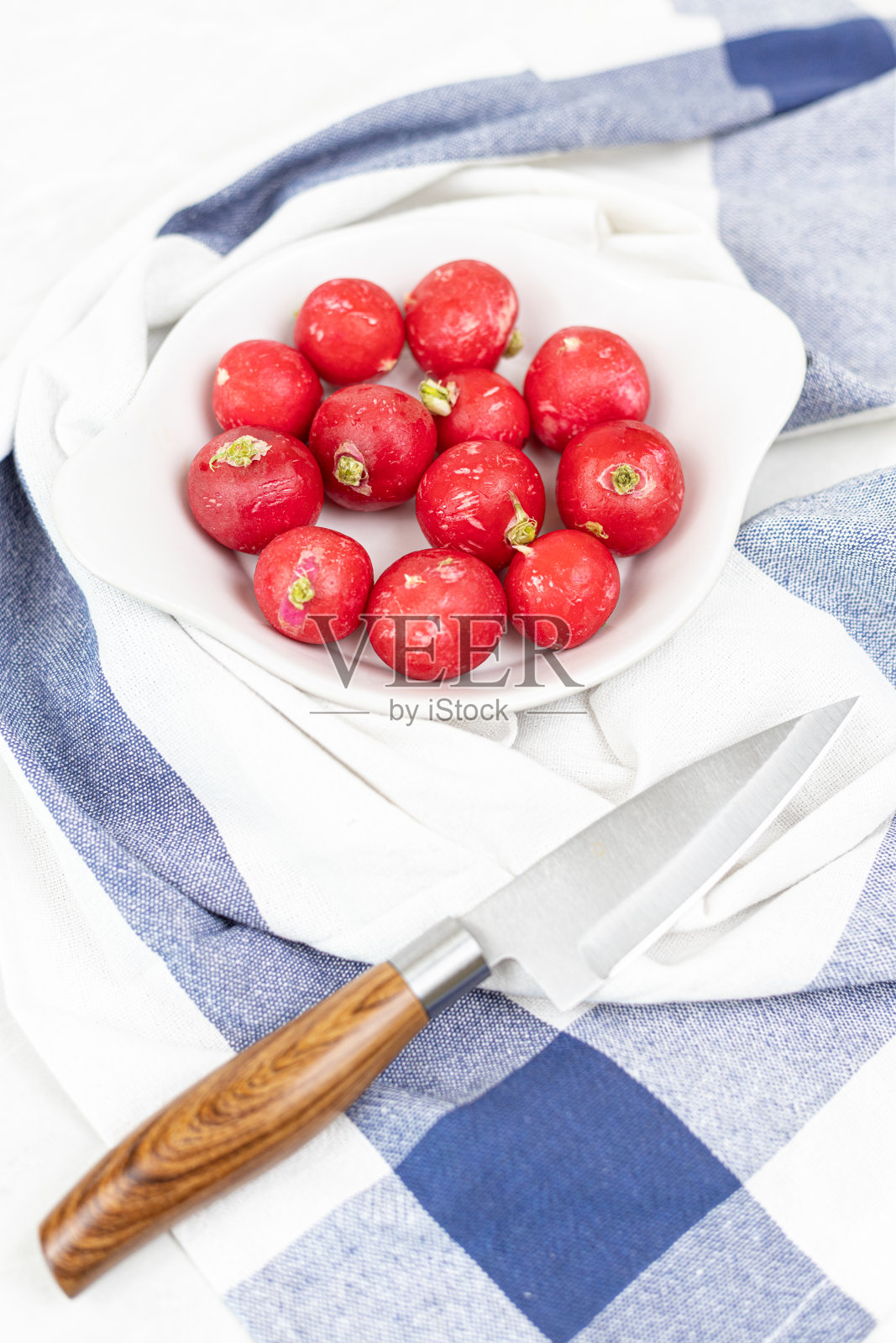 红红的萝卜放在碗里,刀放在桌上照片摄影图片