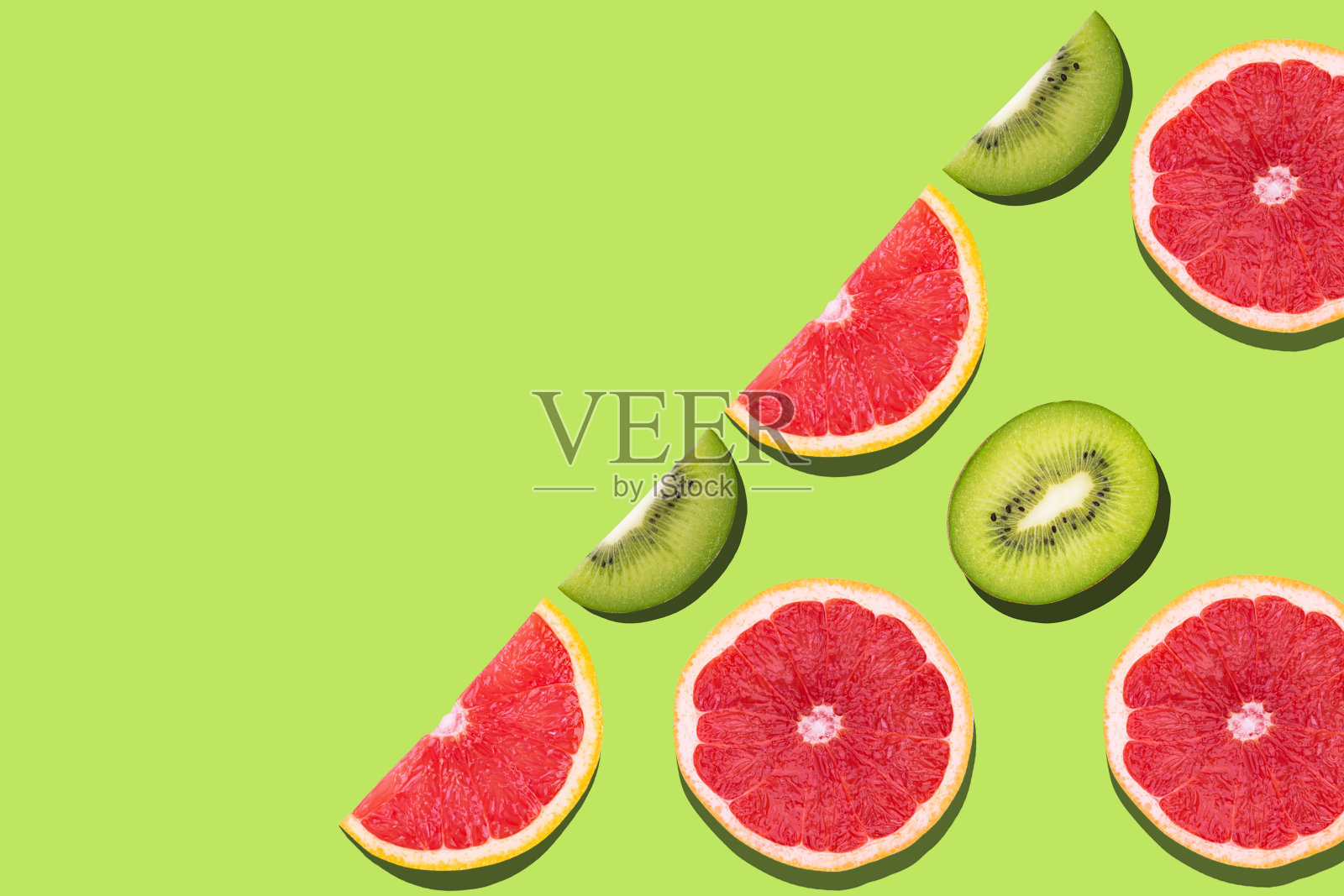 鲜葡萄柚切片的水果图案平铺在绿色的背景上。照片摄影图片