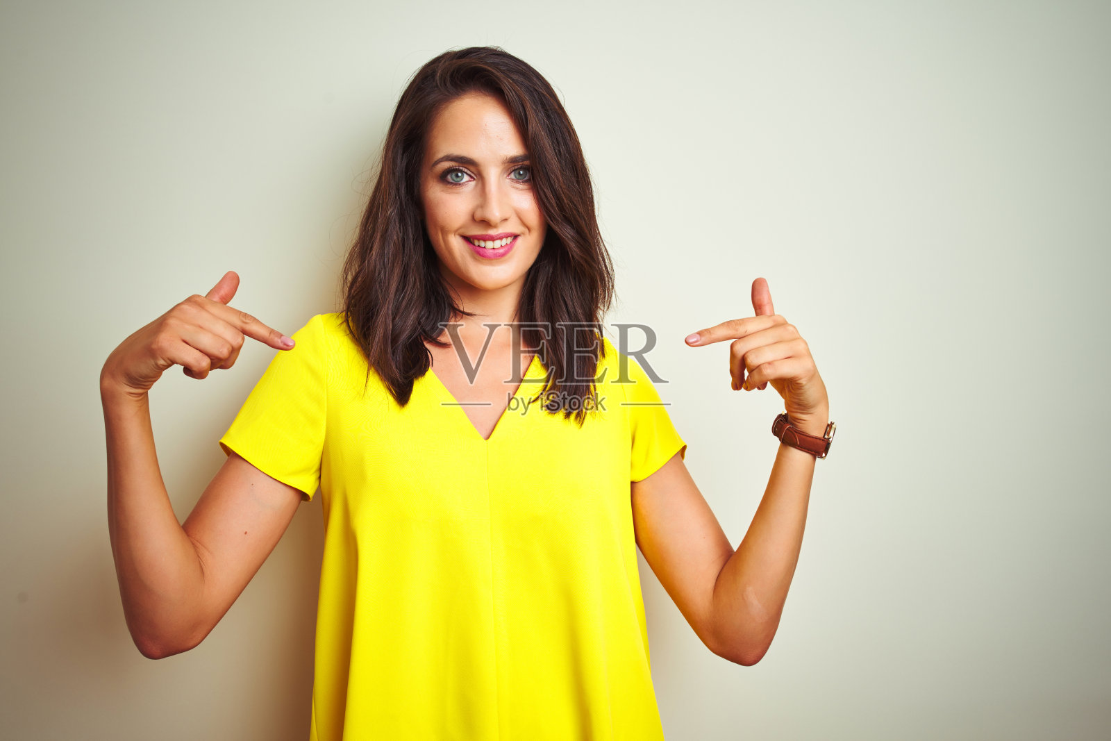 年轻美丽的女人穿着黄色的t恤站在白色孤立的背景看起来自信的微笑在脸上,用手指指着自己骄傲和幸福。照片摄影图片