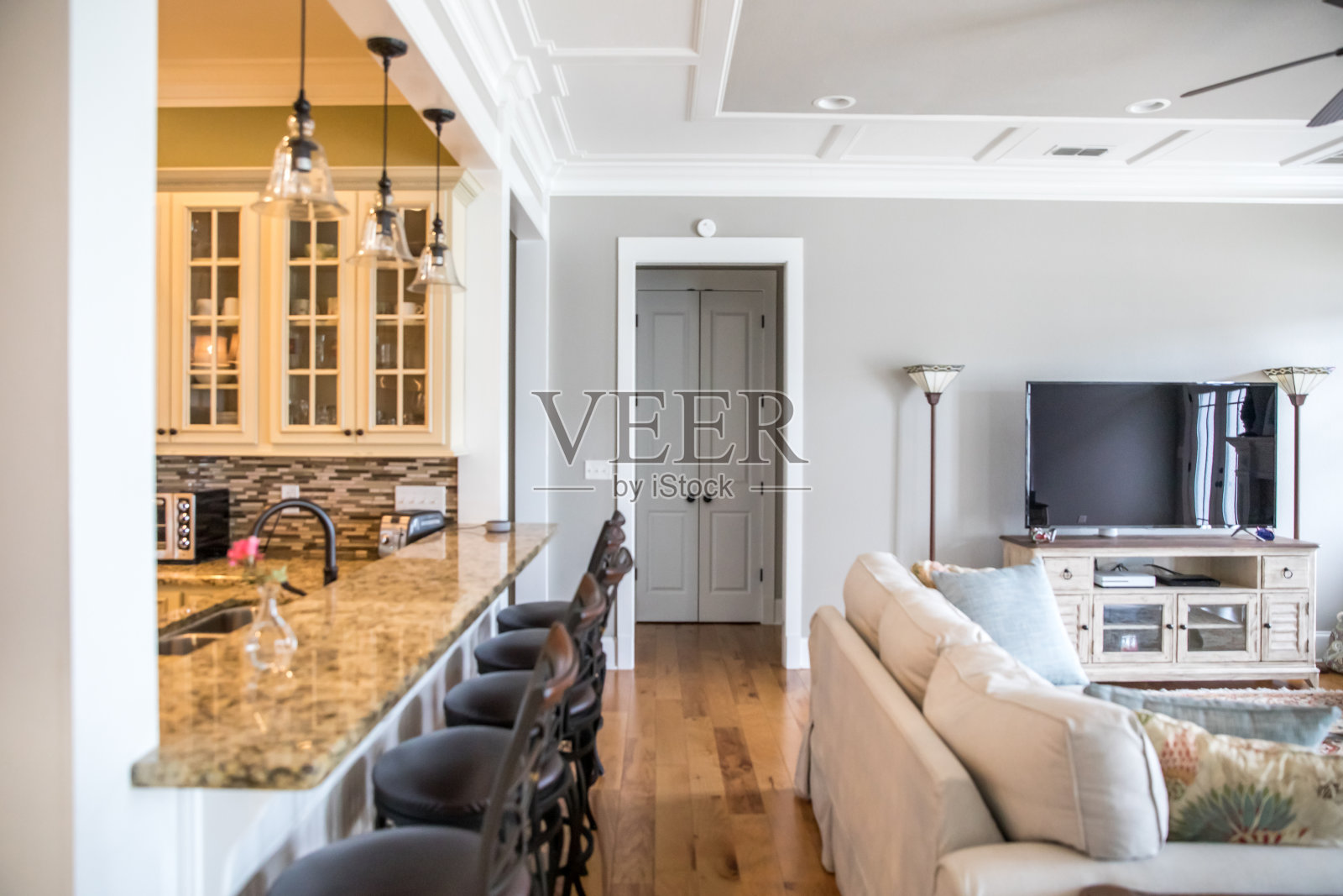 开放式平面住宅的半视图,部分厨房带有酒吧凳,部分自然浅灰色客厅和书房带有家具照片摄影图片