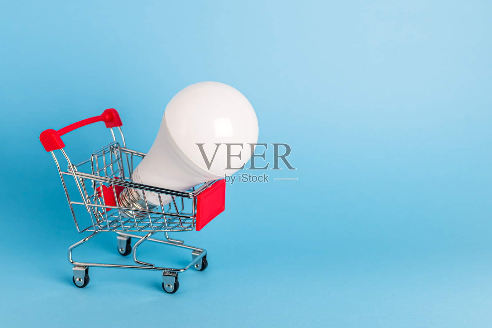 蓝色背景的购物车里的灯泡照片摄影图片