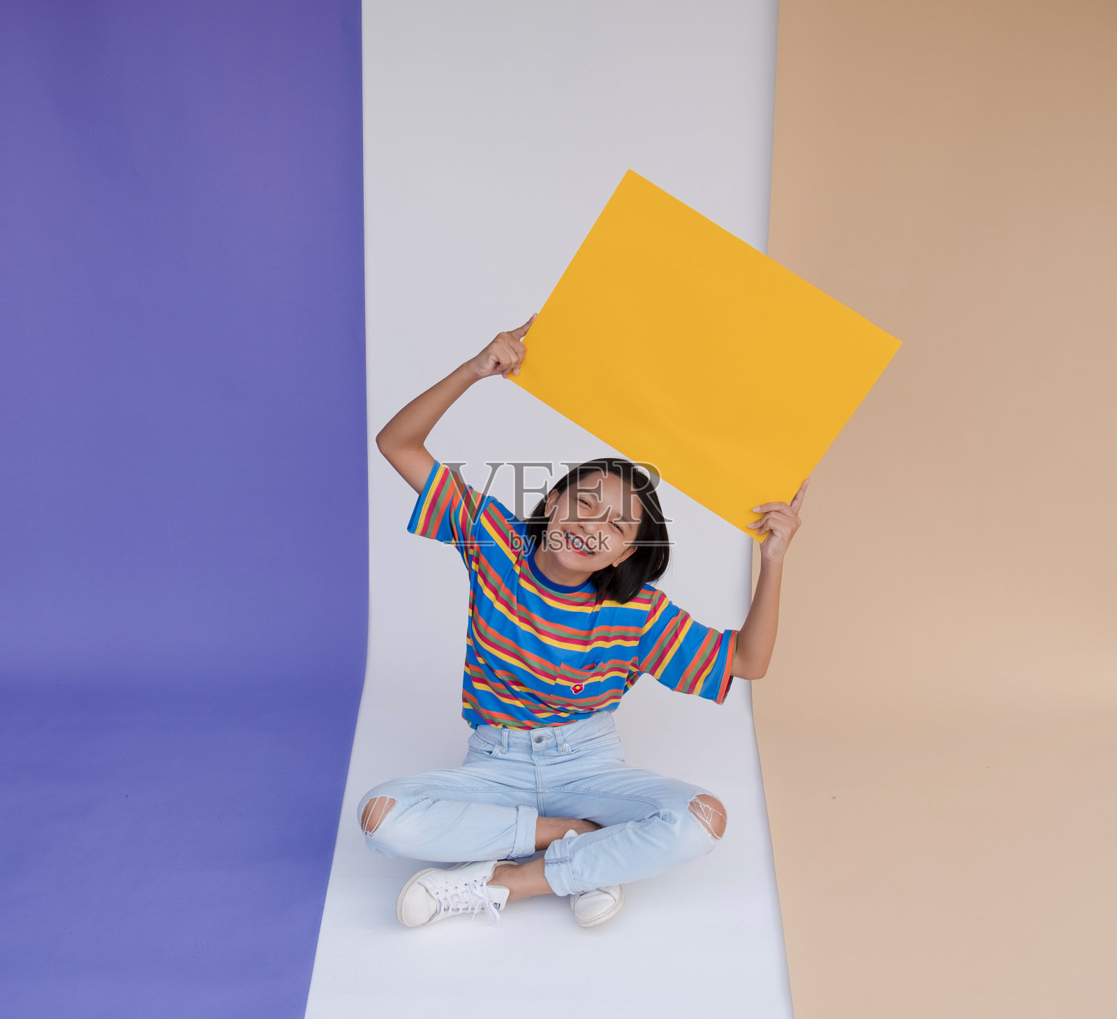 快乐的亚洲年轻女孩持有黄色边框与柔和的背景。照片摄影图片