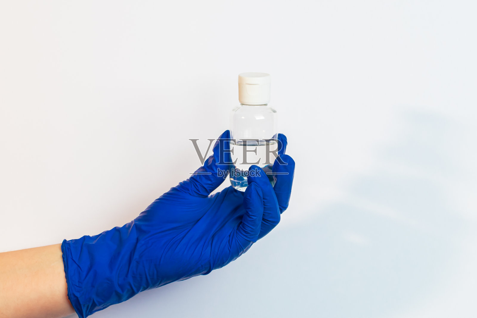 一只戴着蓝色乳胶手套的手拿着消毒剂。预防防范冠状病毒的概念。照片摄影图片