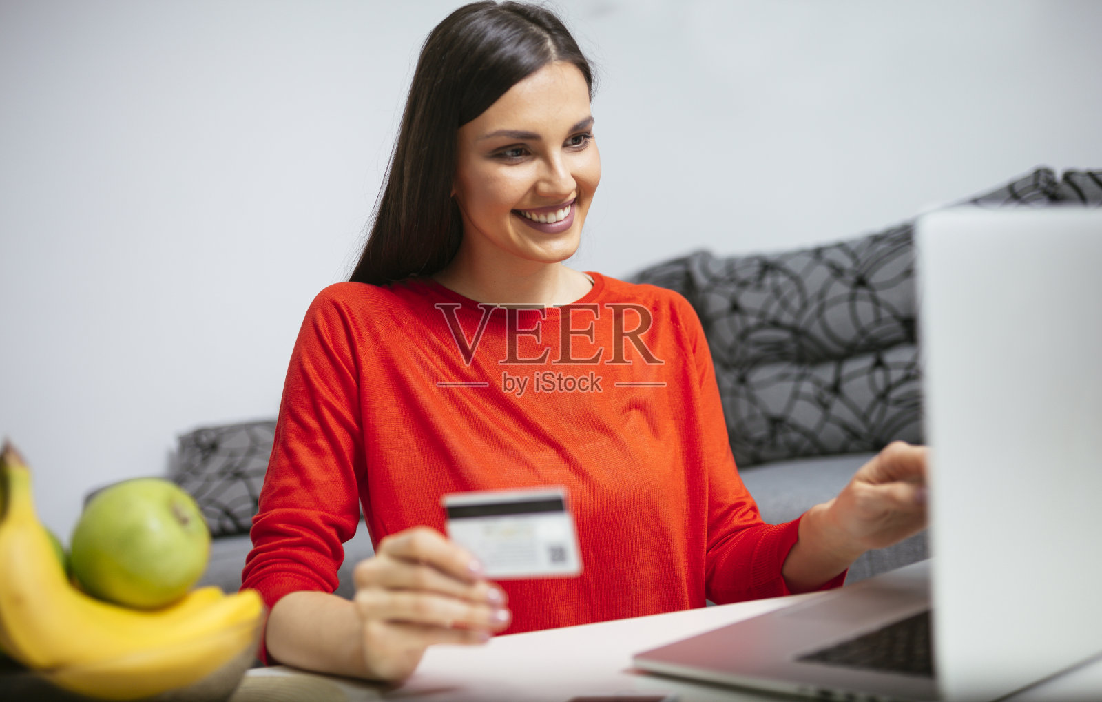 快乐的女人在她的家网上购物照片摄影图片