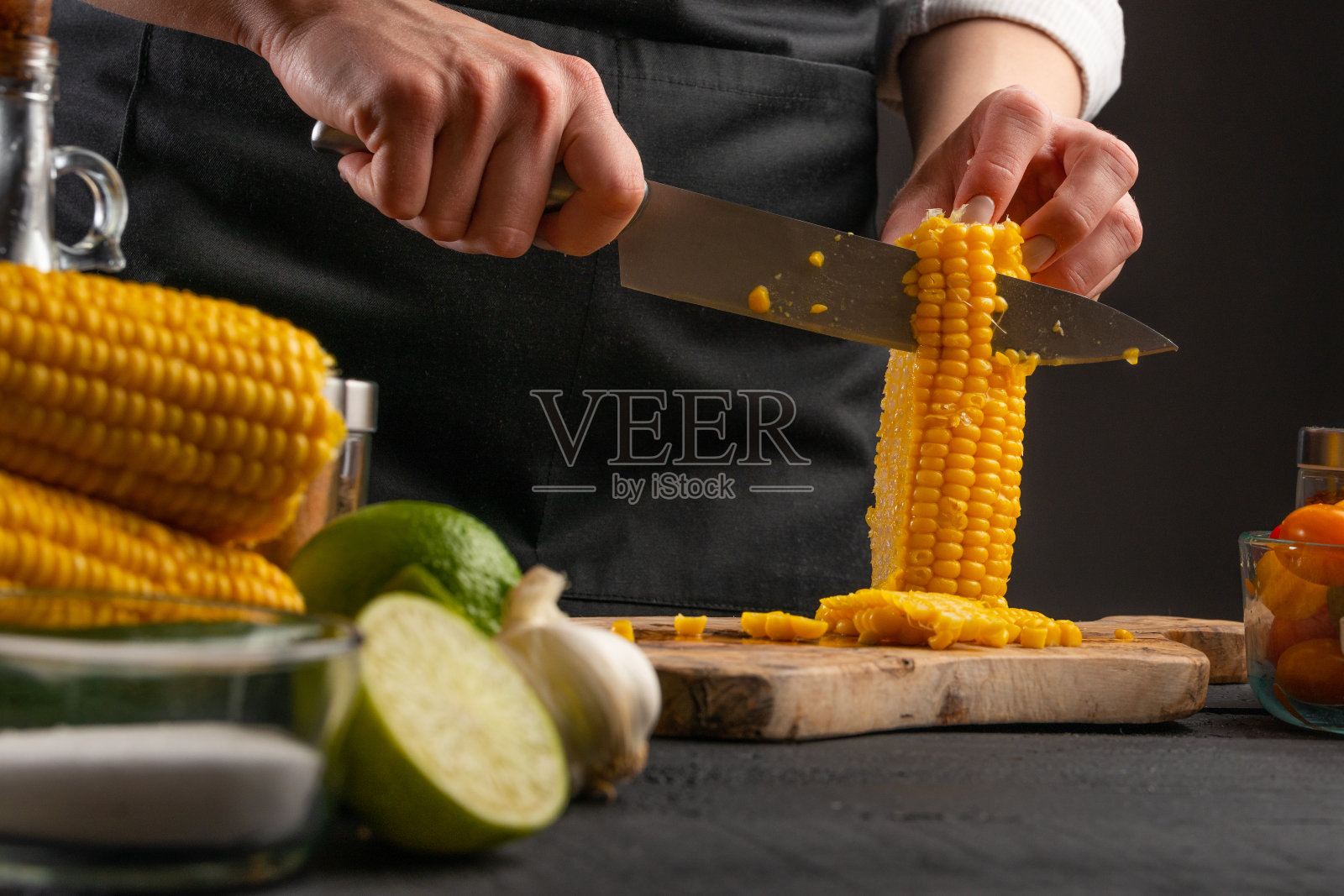 在烹饪过程中,厨师用刀切玉米,将谷物提取成沙拉。烹饪,餐饮,家庭食谱。照片摄影图片