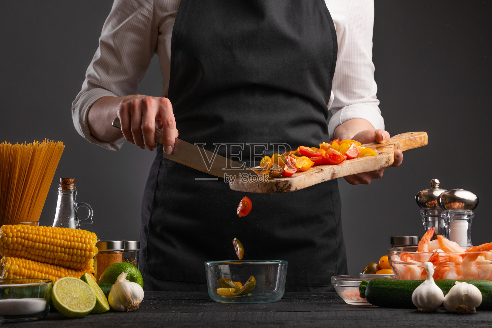 厨师把圣女果切好,倒出来做虾仁沙拉。商务餐厅正在准备美味健康的食物。照片摄影图片