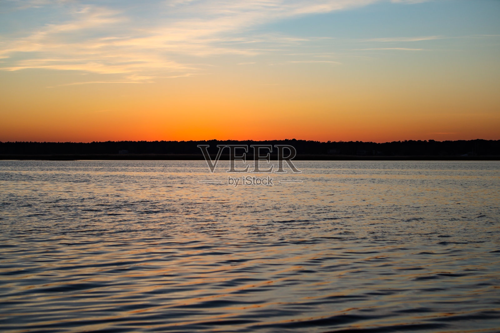 美丽的风景与河流缓慢流动与小波浪在日落。照片摄影图片