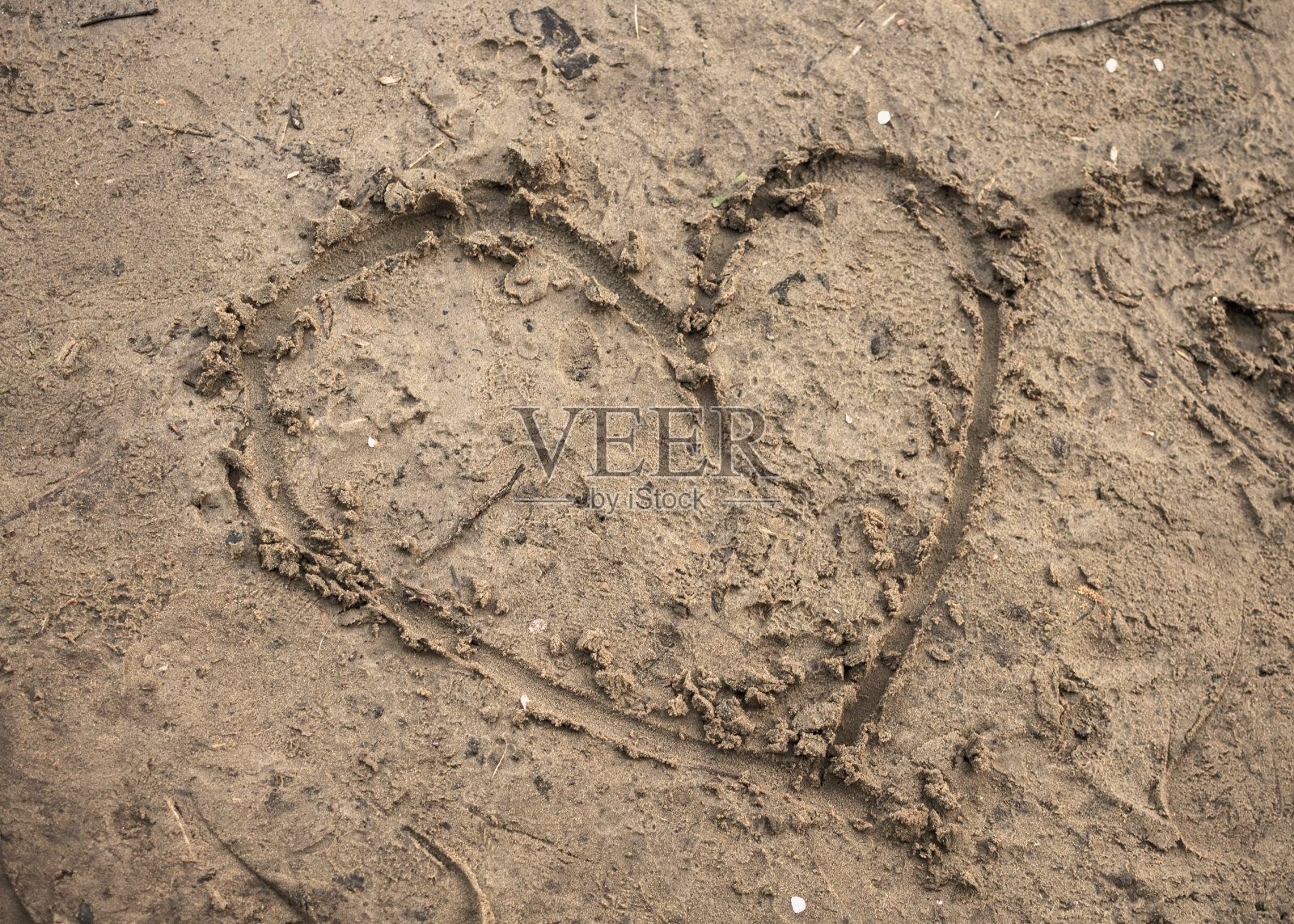 湿沙中的心的特写画。照片摄影图片