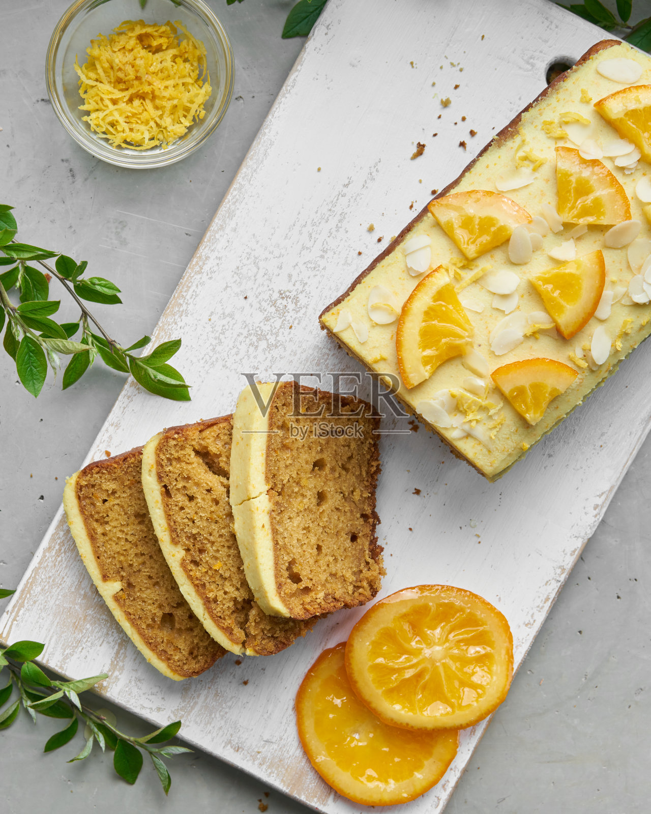 素橙面包蛋糕和切片。自制的柑橘蛋糕,上面有白腰果奶油。绿色的春天到处都是树叶。照片摄影图片