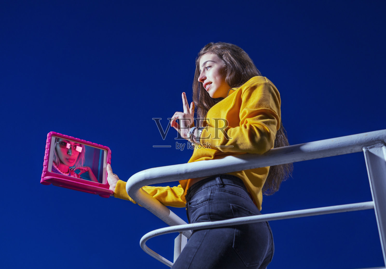 少女电视会议在日落与平板电脑从家阳台照片摄影图片