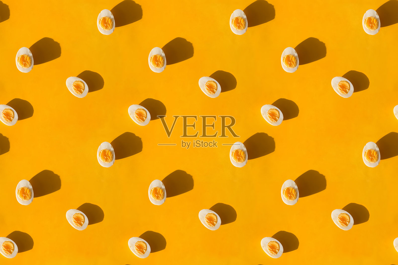 煮熟的鸡蛋,在黄色的背景上切成两半,平躺着。照片摄影图片