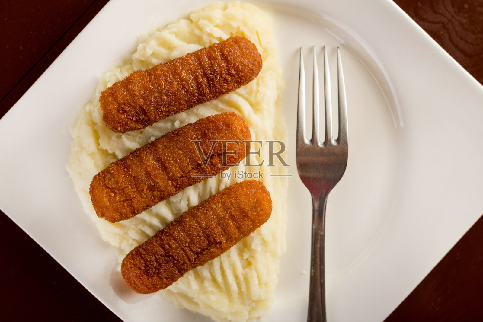 平铺在盘子上,配上鱼条和土豆泥照片摄影图片