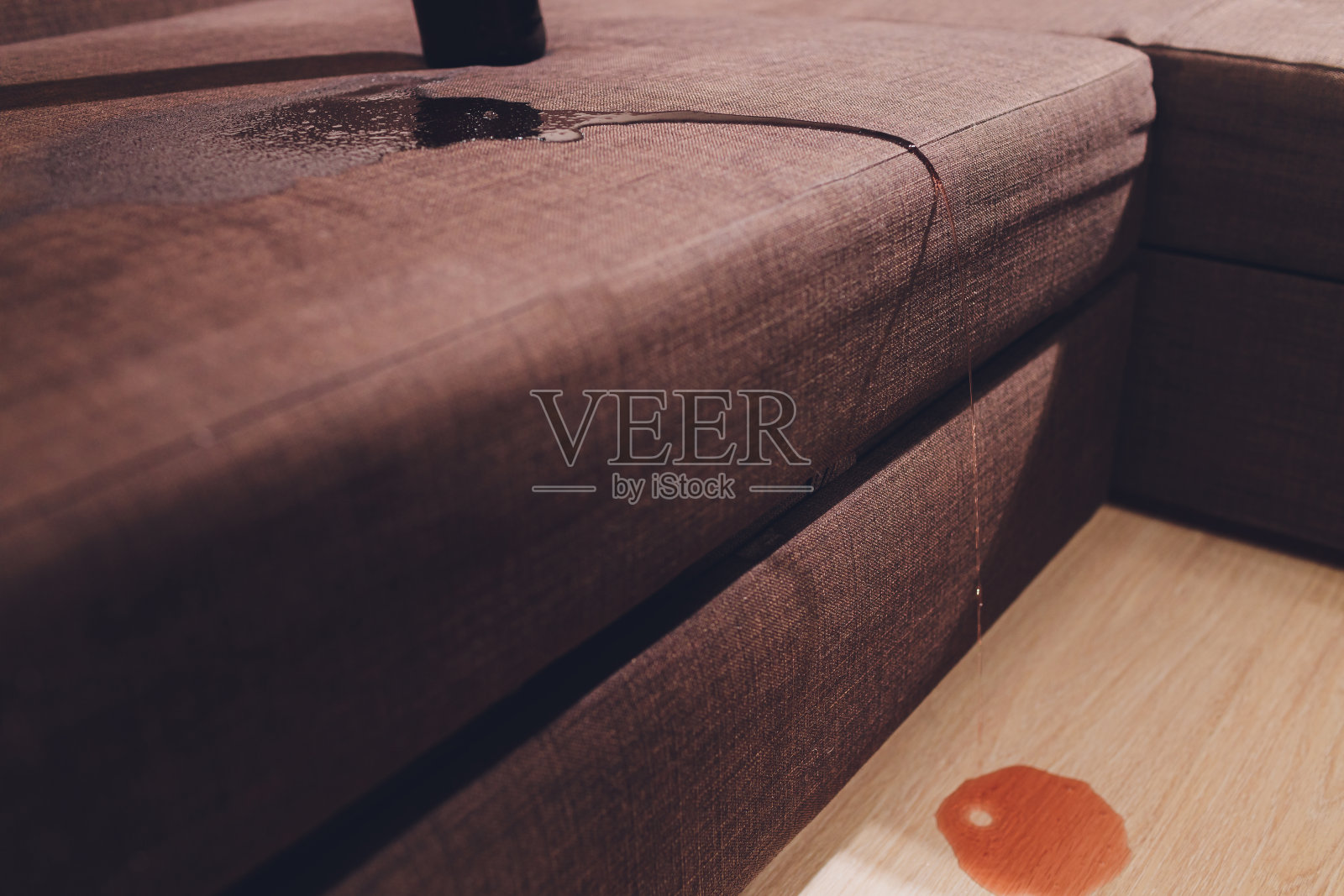 红酒洒在了棕色的沙发上。照片摄影图片