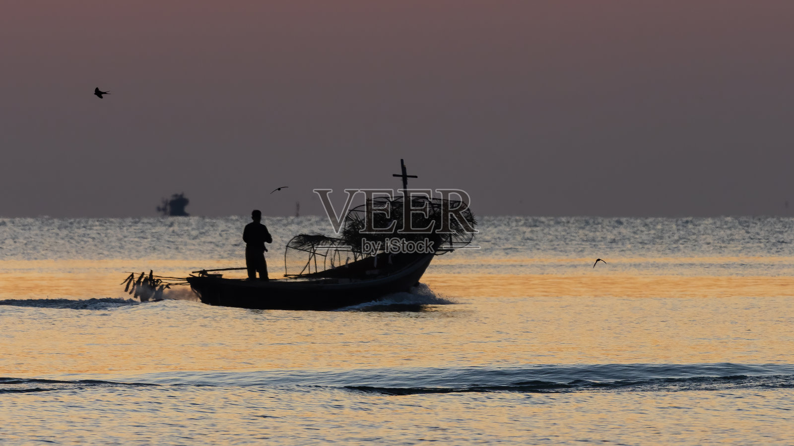泰国传统渔船的剪影与日出的金色辉光和水面上升起的太阳的倒影的背景。照片摄影图片
