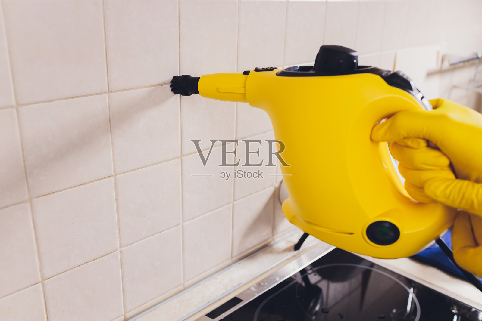 年轻人正在用蒸汽清洁器清洁厨房。照片摄影图片