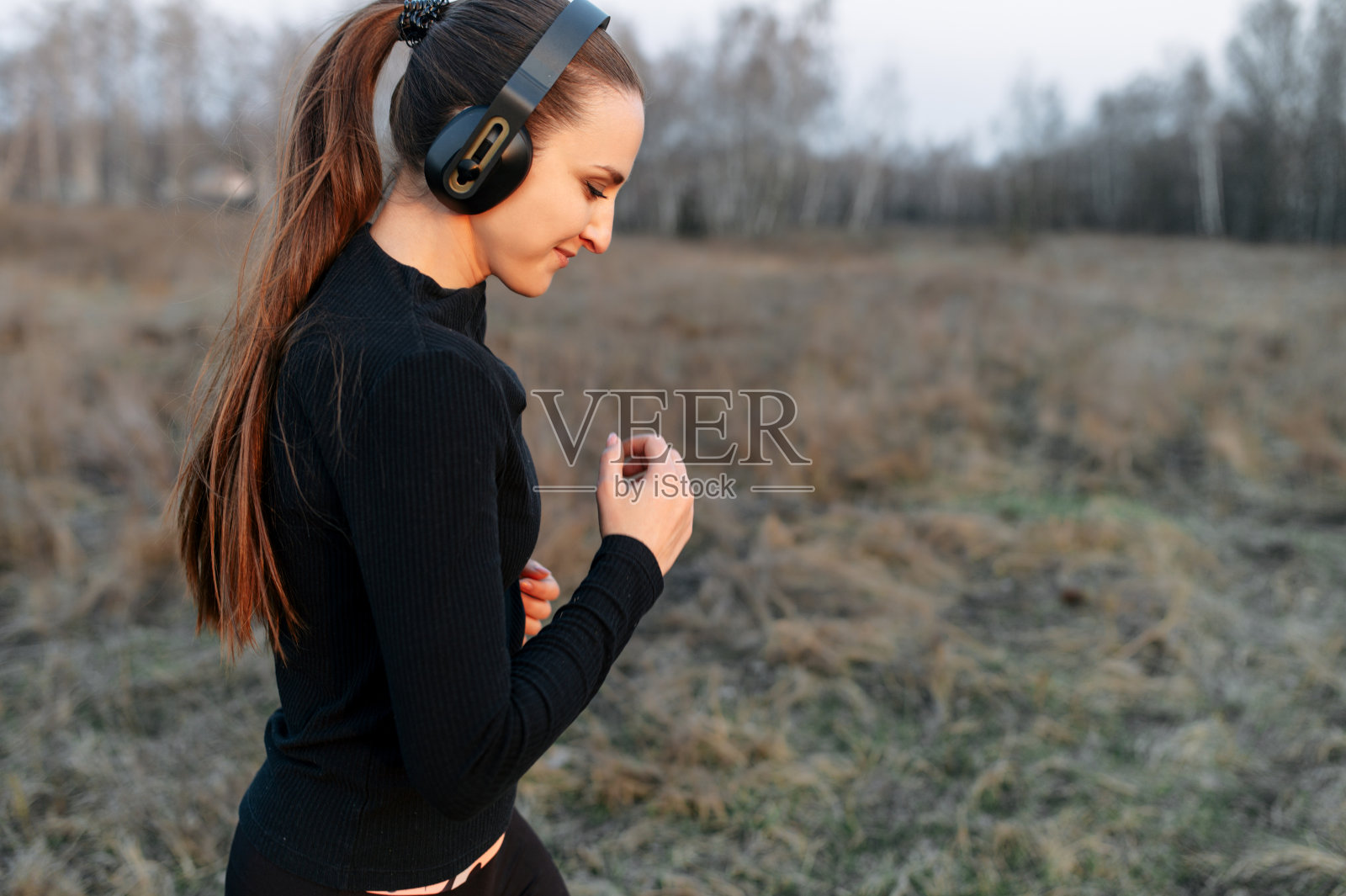 穿着全套黑色运动服的女人在户外跑步照片摄影图片
