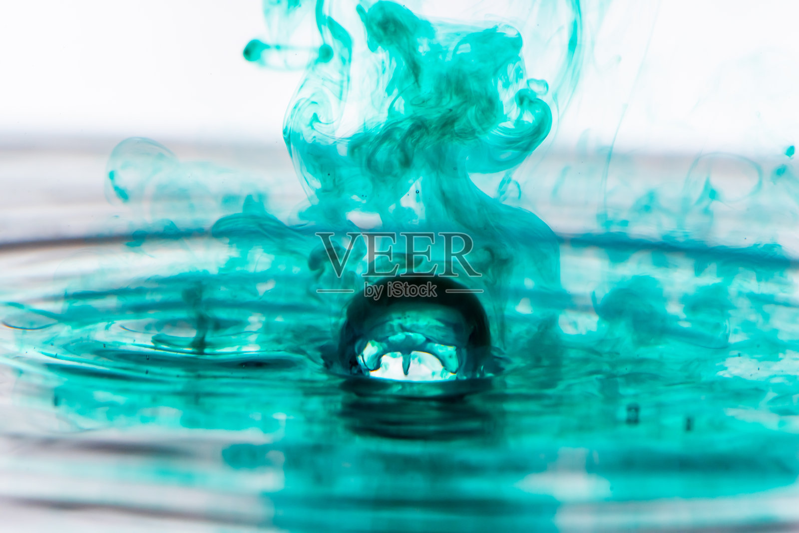 绿色的水滴在清澈的水中飞溅。照片摄影图片