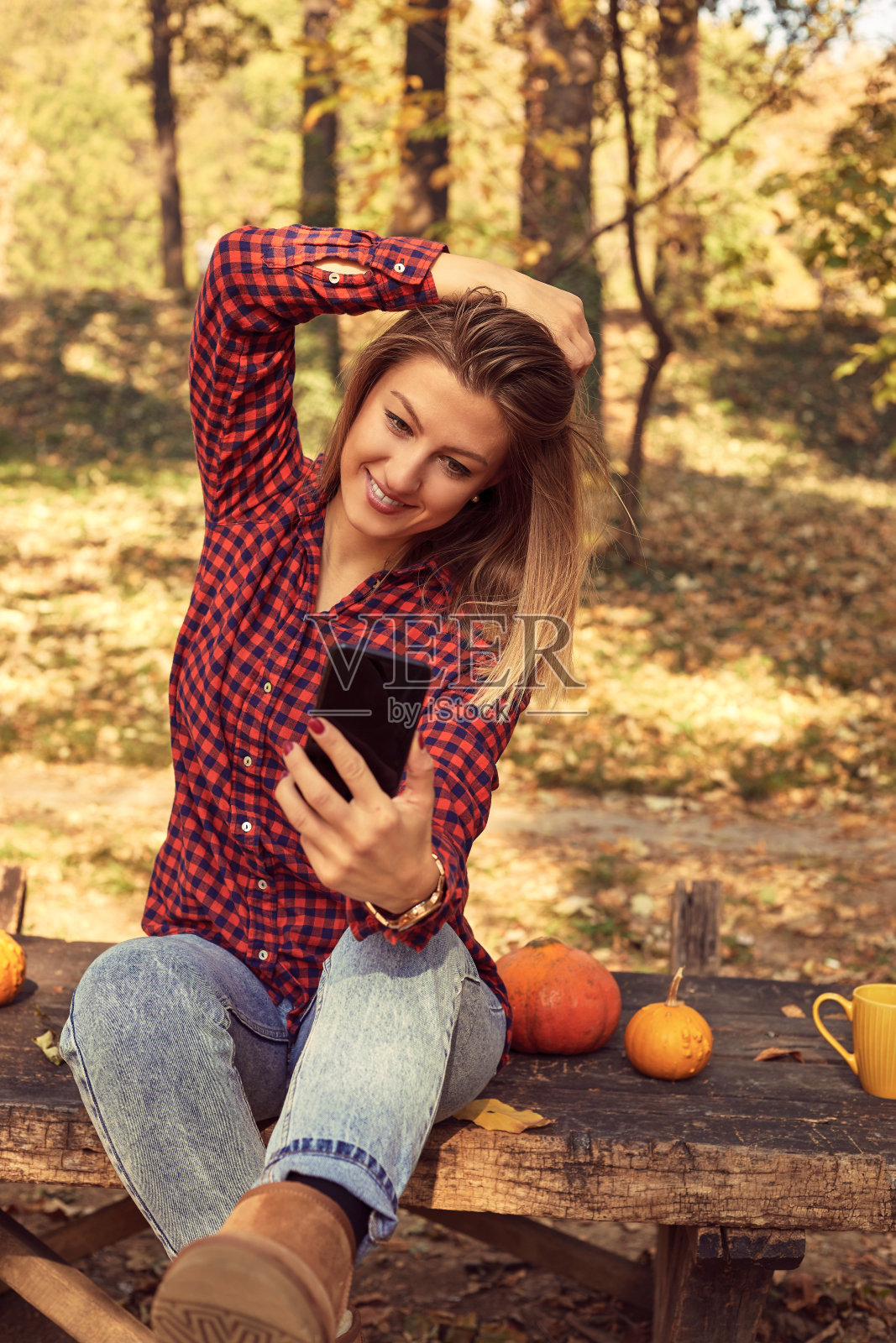 迷人的女人在她的手机和享受秋天的一天。照片摄影图片