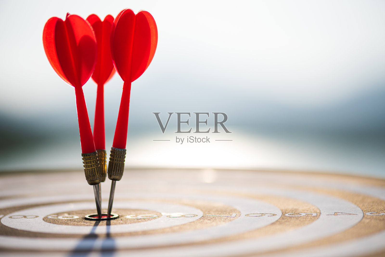 近距离射击红色飞镖箭在目标中心在深蓝色的天空背景。商业目标或目标成功与赢家的概念。照片摄影图片