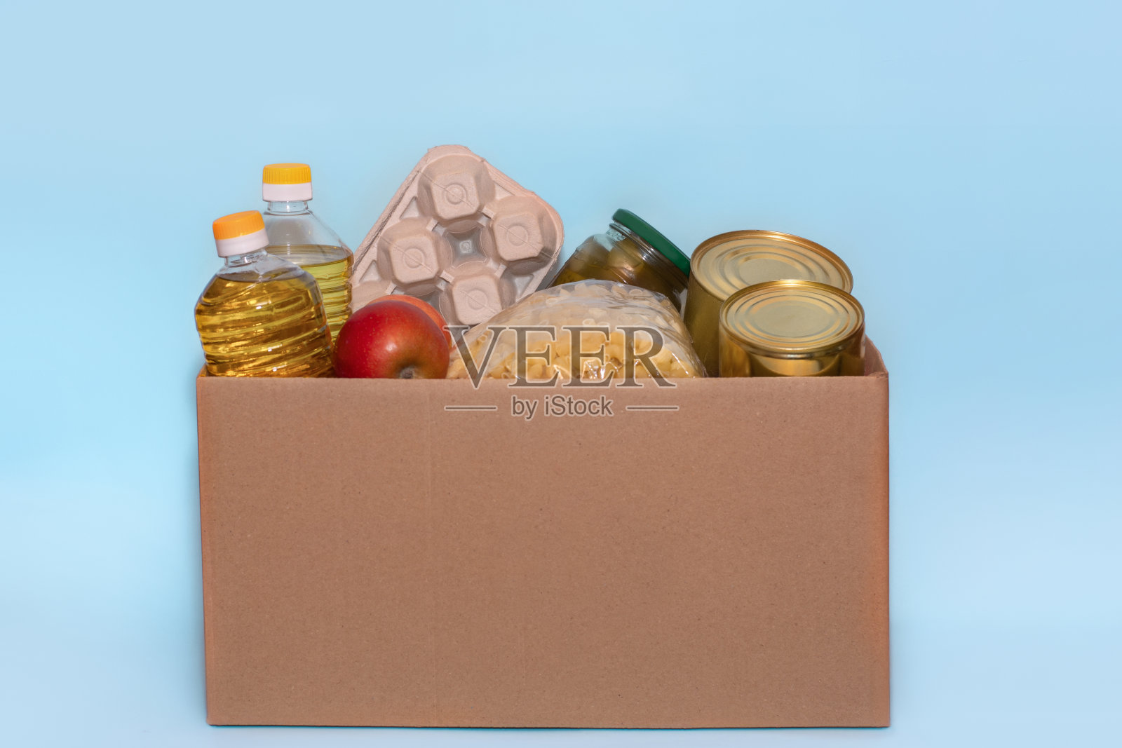 食物在捐赠纸板盒,孤立在蓝色背景,拷贝空间。冠状病毒救援资金和捐赠。慈善捐款。向粮食银行捐款照片摄影图片